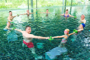 Mehrere Menschen mit Sportgeräten im Schwimmbecken