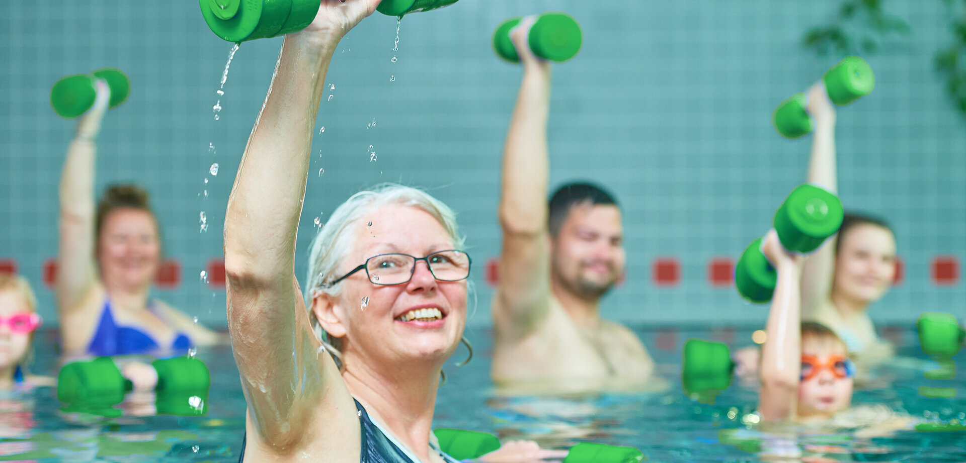 Mehrere Menschen mit Sportgeräten im Schwimmbecken